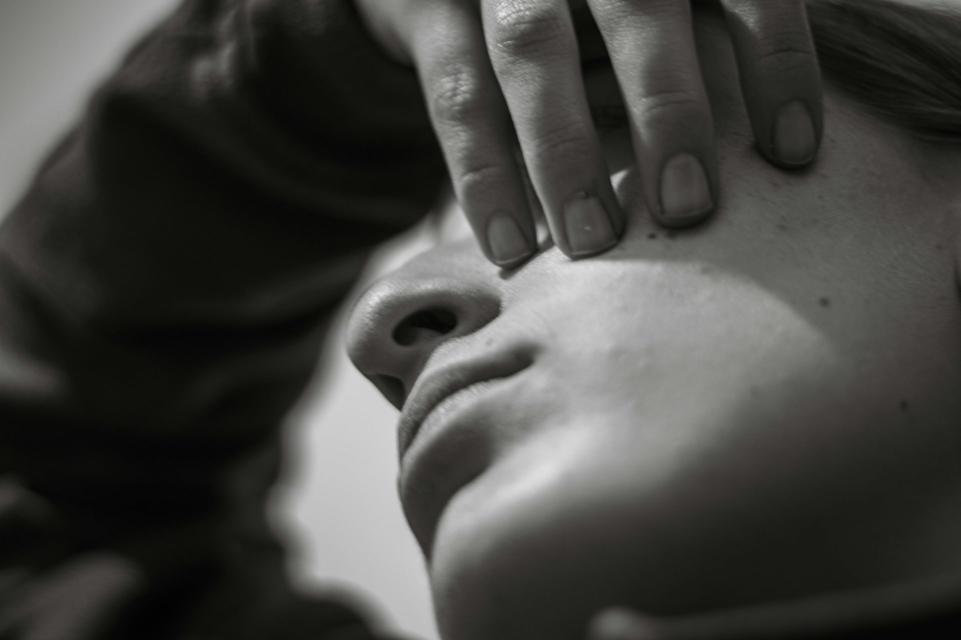 Close-up of a person's face with hand covering eye